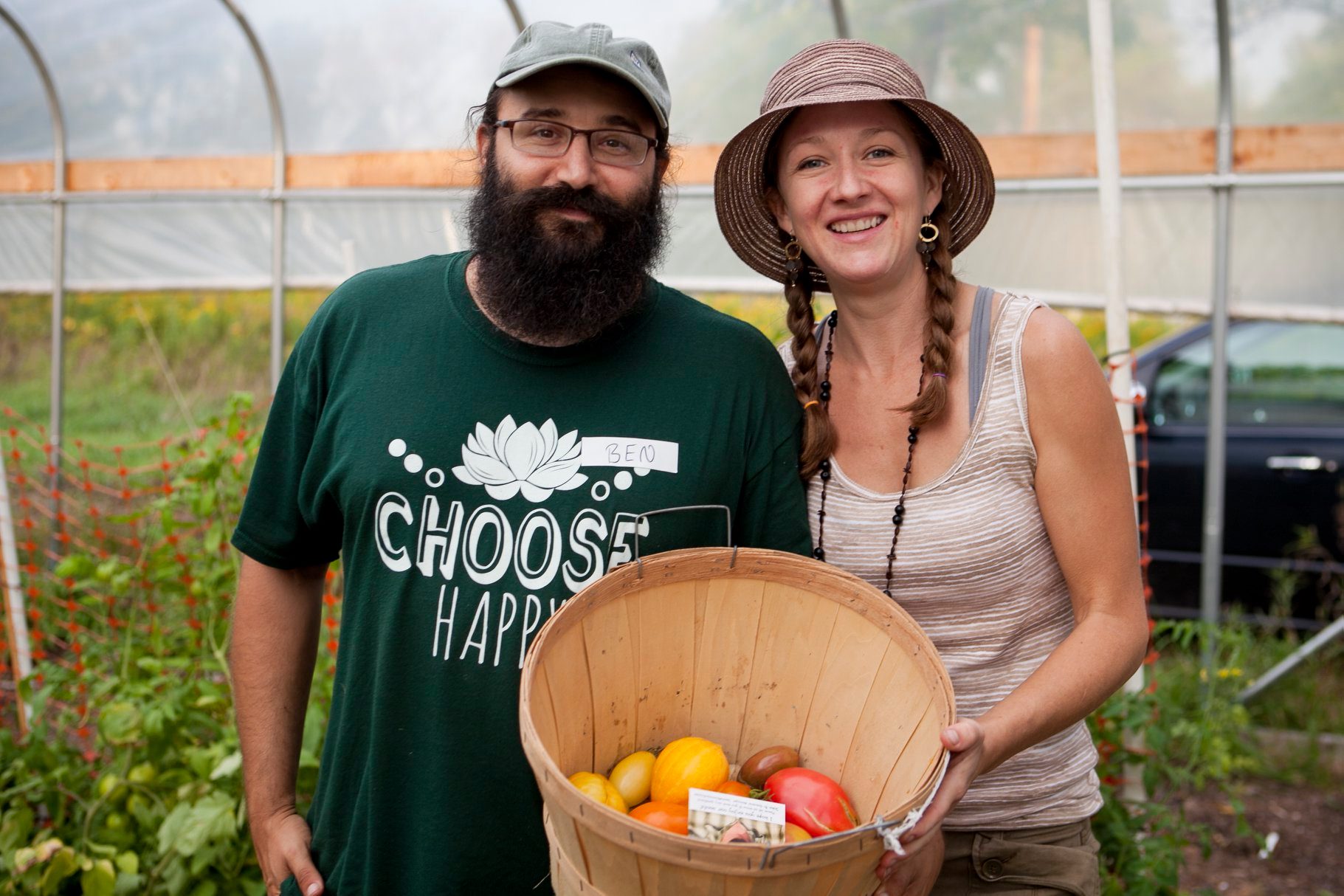 Farmers in a Hoop House holding a basket of tomatoes